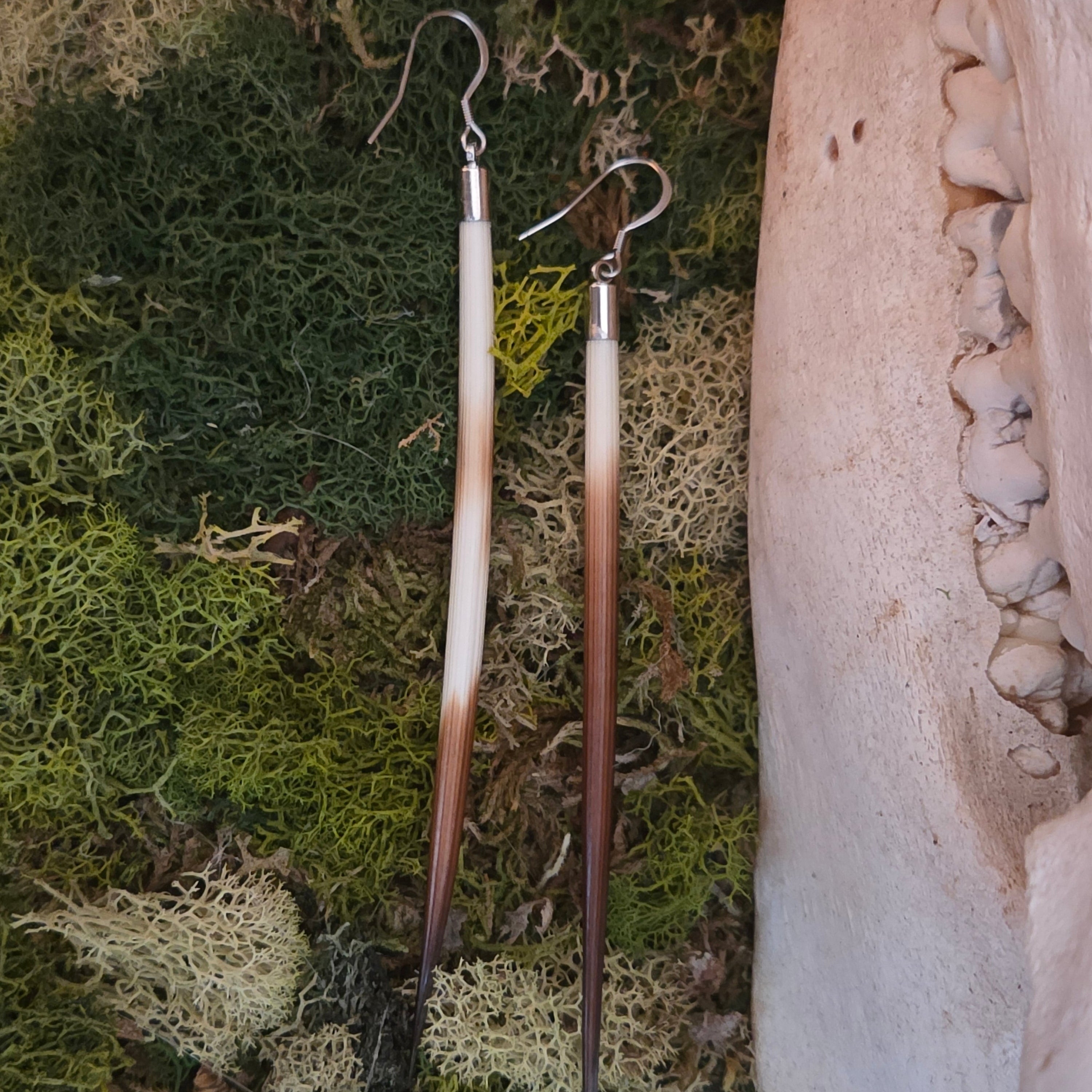 Goblincore earrings behind preserved moss to show you the gorgeous quill colors.